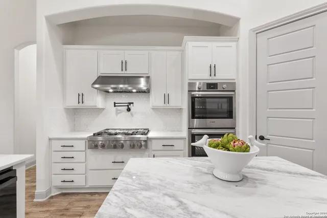a kitchen with a stove and white cabinets