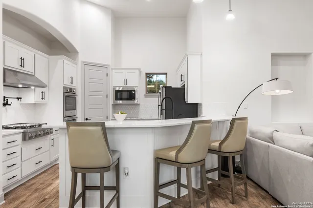 a kitchen with stainless steel appliances kitchen island granite countertop a table chairs sink and cabinets