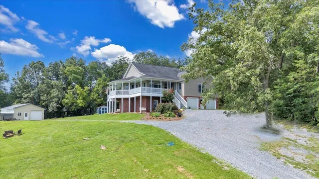 a view of a house next to a big yard and large trees