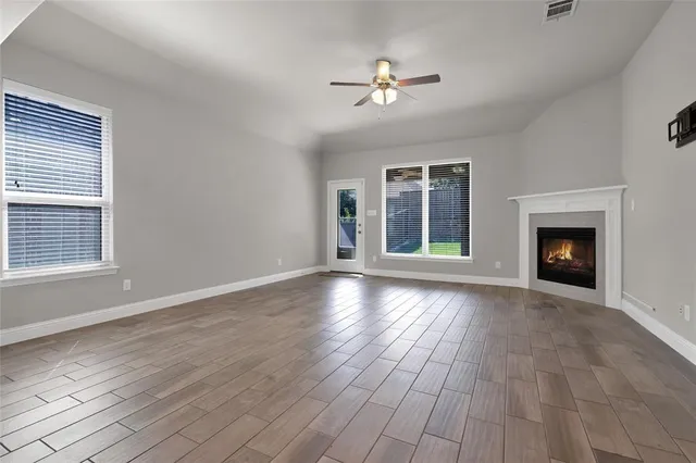 a view of an empty room with wooden floor fireplace and a window
