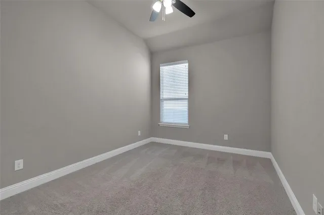 an empty room with a chandelier fan and windows