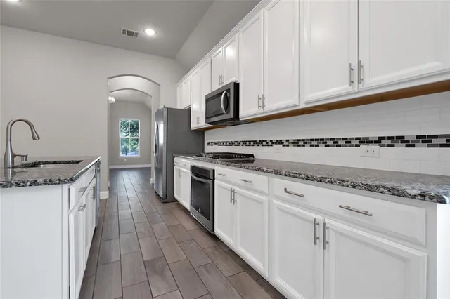 a kitchen with stainless steel appliances granite countertop a stove a sink and a microwave