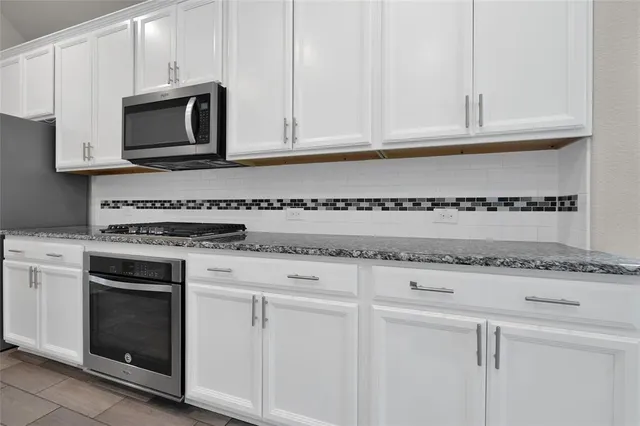 a kitchen with granite countertop white cabinets and a stove a oven with white countertops