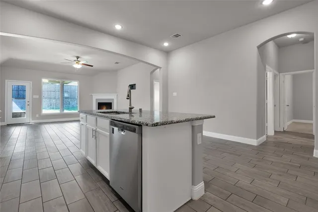 a view of a kitchen with kitchen island a counter top space a sink a stove and a refrigerator