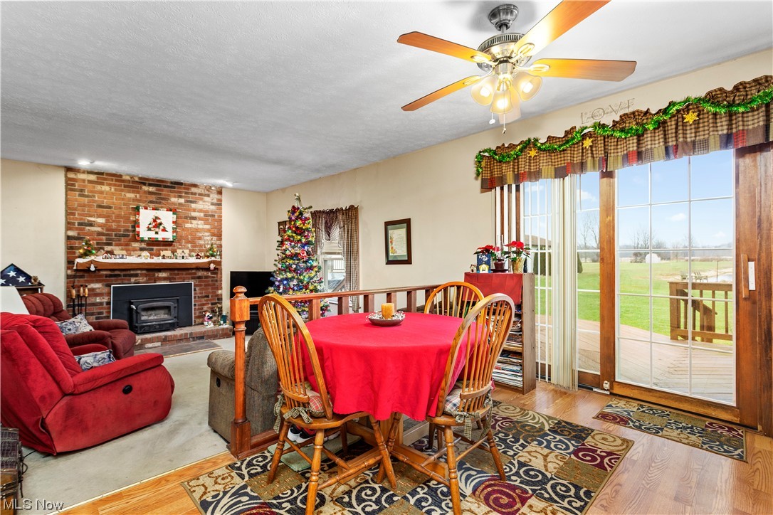 3465 Yost Road Litchfield, OH 44253 - Photo 6 of 27 Dining area with a fireplace, a textured ceiling, ceiling fan, and light wood-type flooring