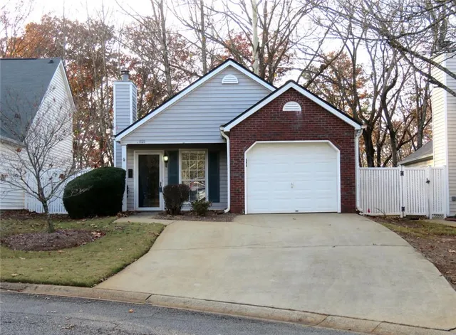 a front view of a house with yard and trees in the background
