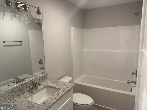 a bathroom with a granite countertop sink a toilet and shower