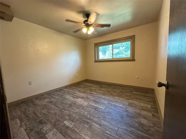 an empty room with ceiling fan and window