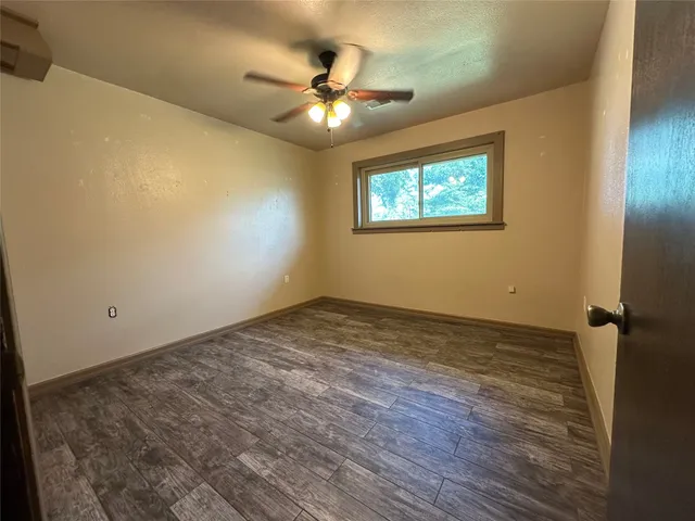 an empty room with ceiling fan and window