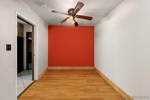 en empty room with wooden floor and fan