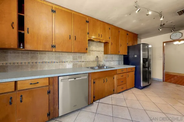a kitchen with stainless steel appliances granite countertop a sink counter space cabinets and a refrigerator