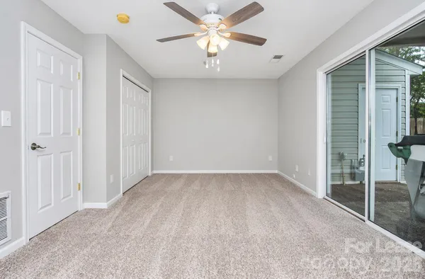 an empty room with closet and a chandelier fan