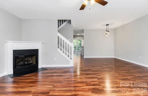 a view of a livingroom with wooden floor a fireplace and a ceiling fan