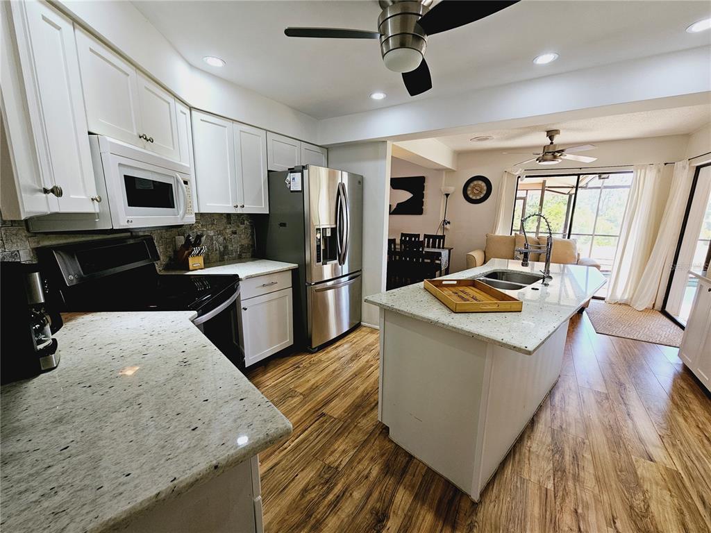 2411 Belle Road Englewood, FL 34223 - Photo 7 of 30 a large kitchen with stainless steel appliances kitchen island granite countertop a sink stove and refrigerator