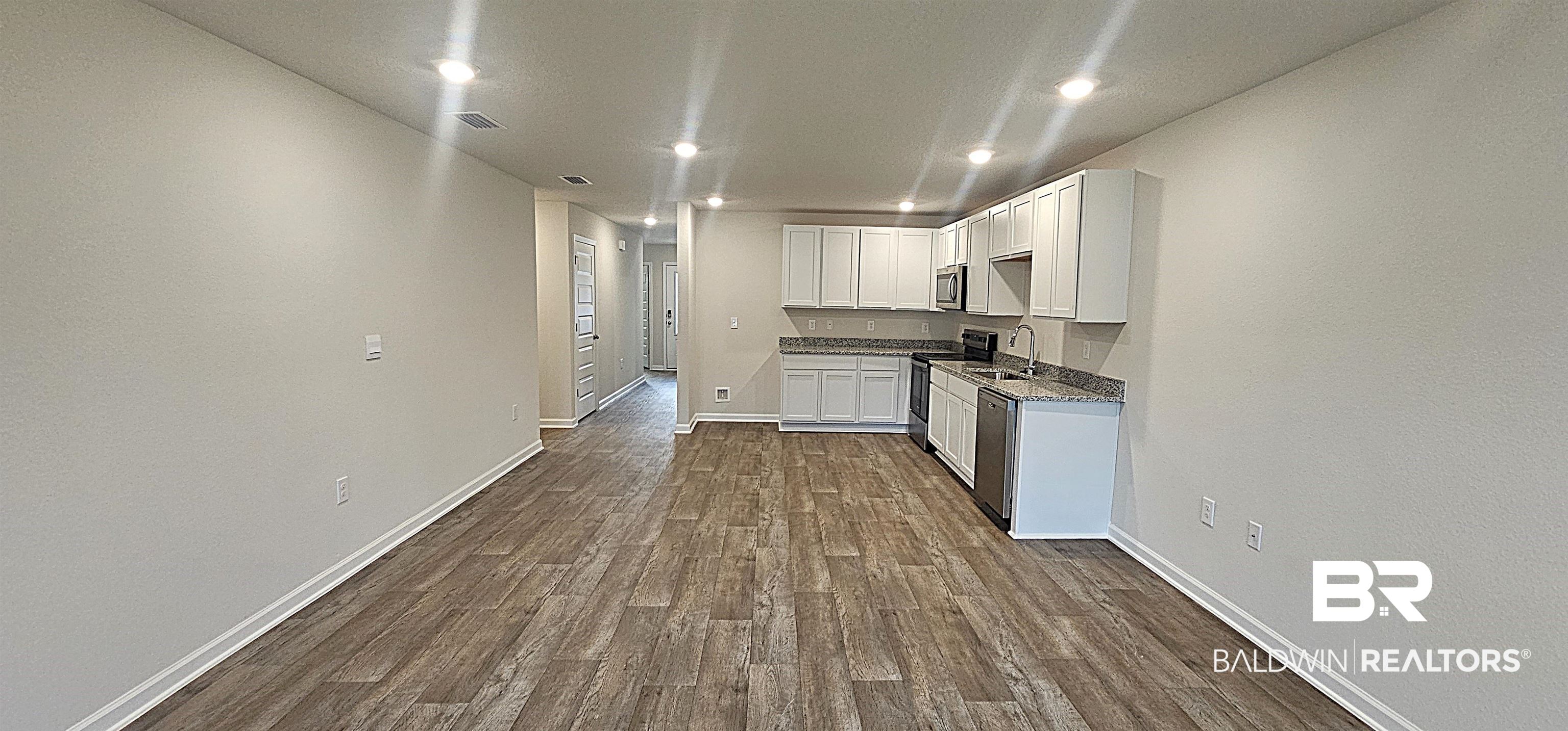 1148 Sweet Laurel Street Foley, AL 36535 - Photo 11 of 18 Kitchen featuring appliances with stainless steel finishes, white cabinetry, hardwood / wood-style flooring, dark stone counters, and sink