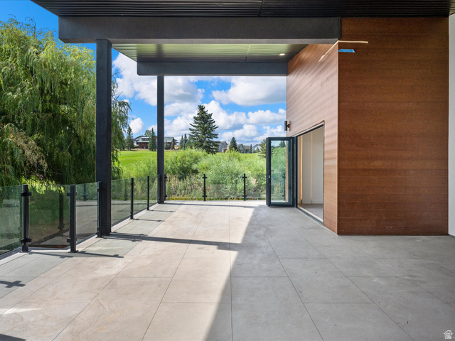 2610 Foxridge Road Garden City, UT 84028 - Photo 48 of 71 Expansive outdoor patio with large format tile flooring, glass panel railing, and wood-paneled exterior wall