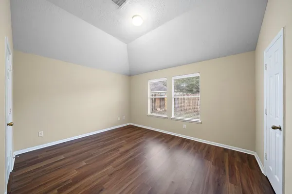 an empty room with wooden floor and windows