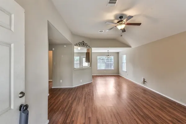a view of an empty room with a window and wooden floor