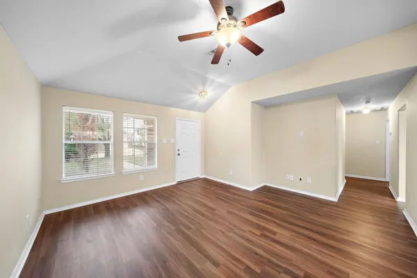 a view of an empty room with wooden floor and a window