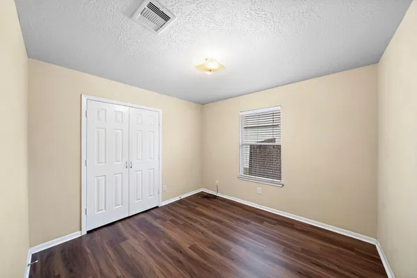 an empty room with wooden floor cabinet and windows