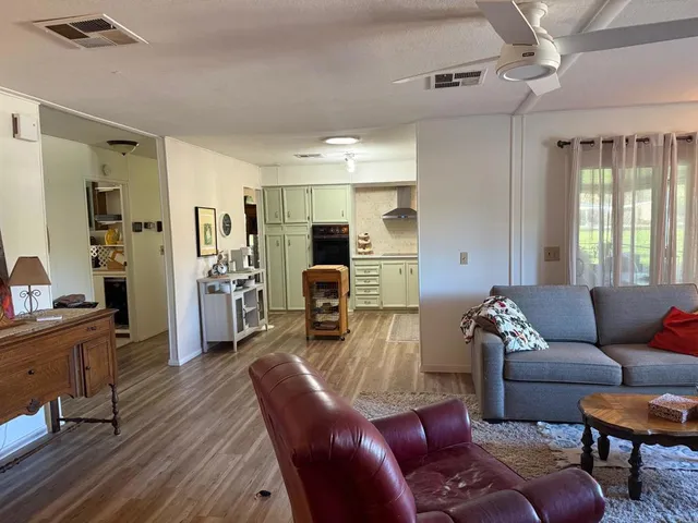a living room with furniture kitchen view and a wooden floor