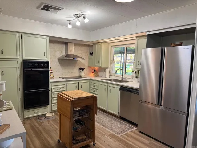 a kitchen with stainless steel appliances a refrigerator a sink a stove and white cabinets