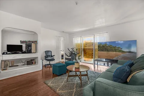 a living room with furniture a flat screen tv and a floor to ceiling window