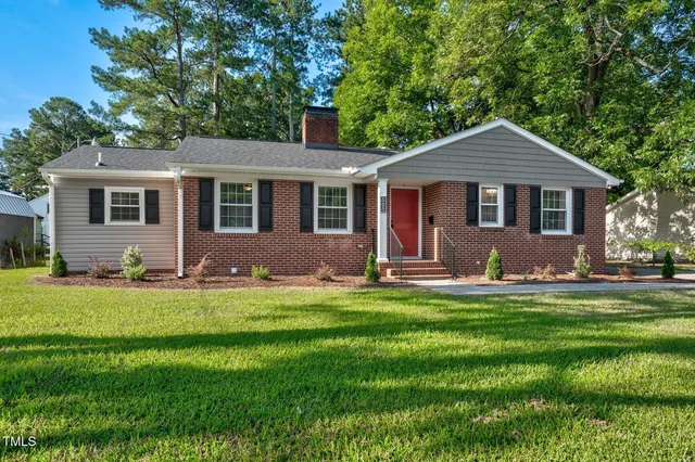 a front view of house with yard and trees in the background