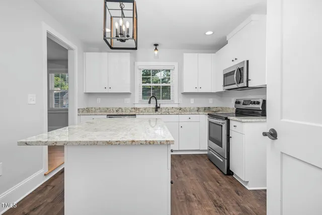 a kitchen with stainless steel appliances granite countertop a sink stove refrigerator and microwave