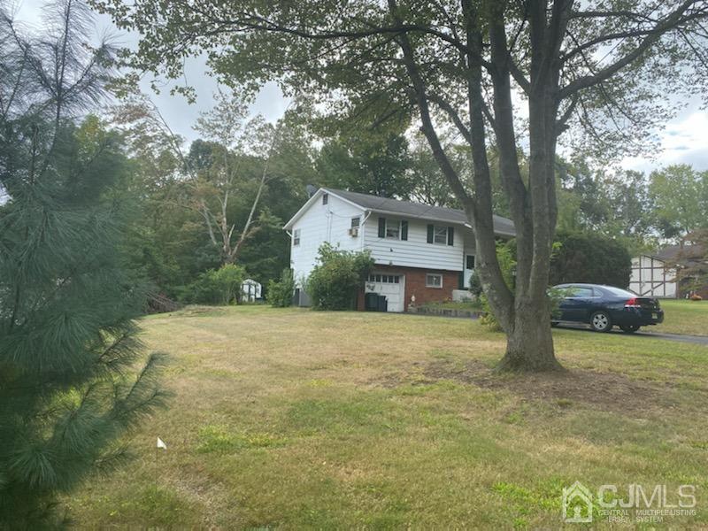 4 Holiday Road Manalapan, NJ 07726 - Photo 4 of 9 a front view of a house with a yard and garage