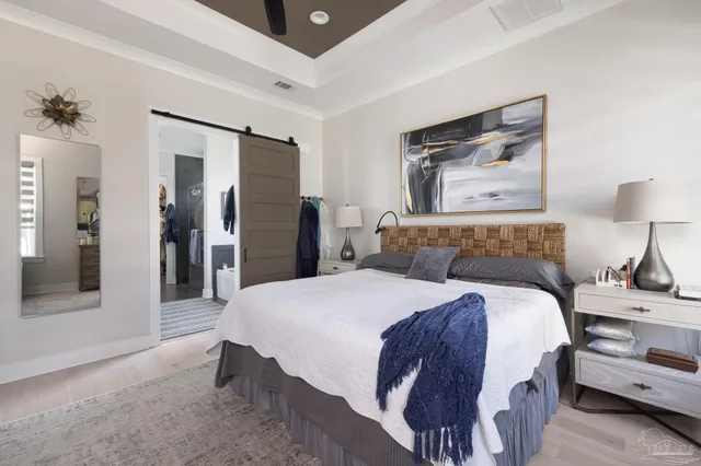 a spacious bedroom with a bed and a lamp on table