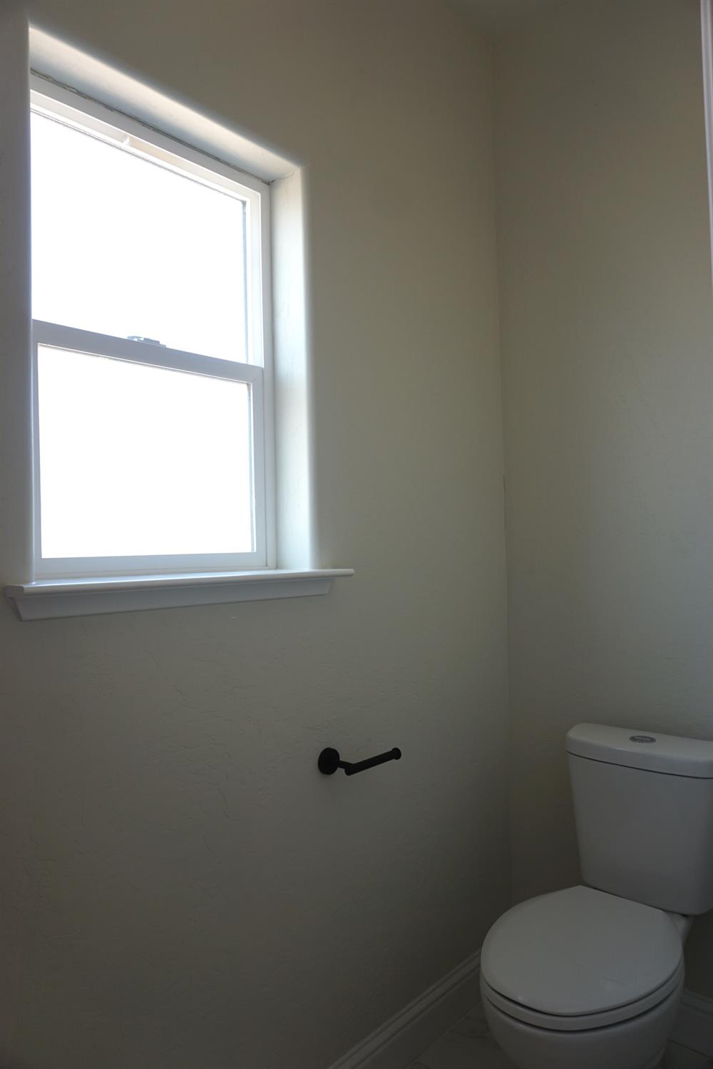 16398 Road 37 Madera, CA 93636 - Photo 9 of 23 a white toilet sitting next to a window in a bathroom