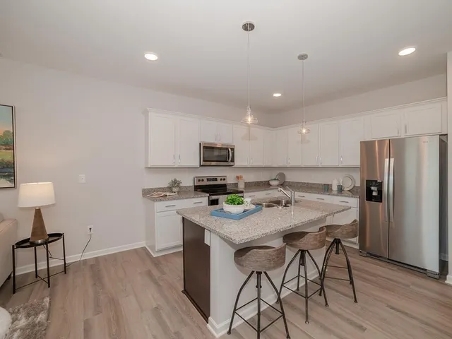 a kitchen with stainless steel appliances granite countertop a table chairs stove refrigerator and cabinets