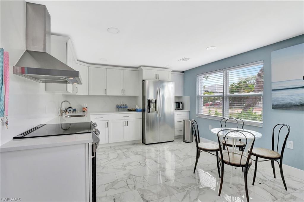 1009 Ridge Street Naples, FL 34103 - Photo 5 of 30 Kitchen featuring stainless steel appliances, light marble finish flooring, white cabinets, and light stone counters
