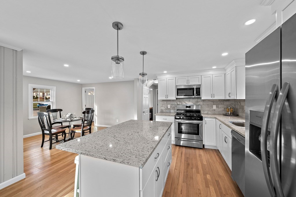 14 Curtis Road Canton, MA 02021 - Photo 6 of 23 a kitchen with stainless steel appliances granite countertop a stove top oven a sink dishwasher a dining table and chairs with wooden floor