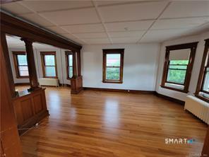 393 Highland Avenue, Unit 2 Waterbury, CT 06708 - Photo 2 of 10 an empty room with wooden floor and windows
