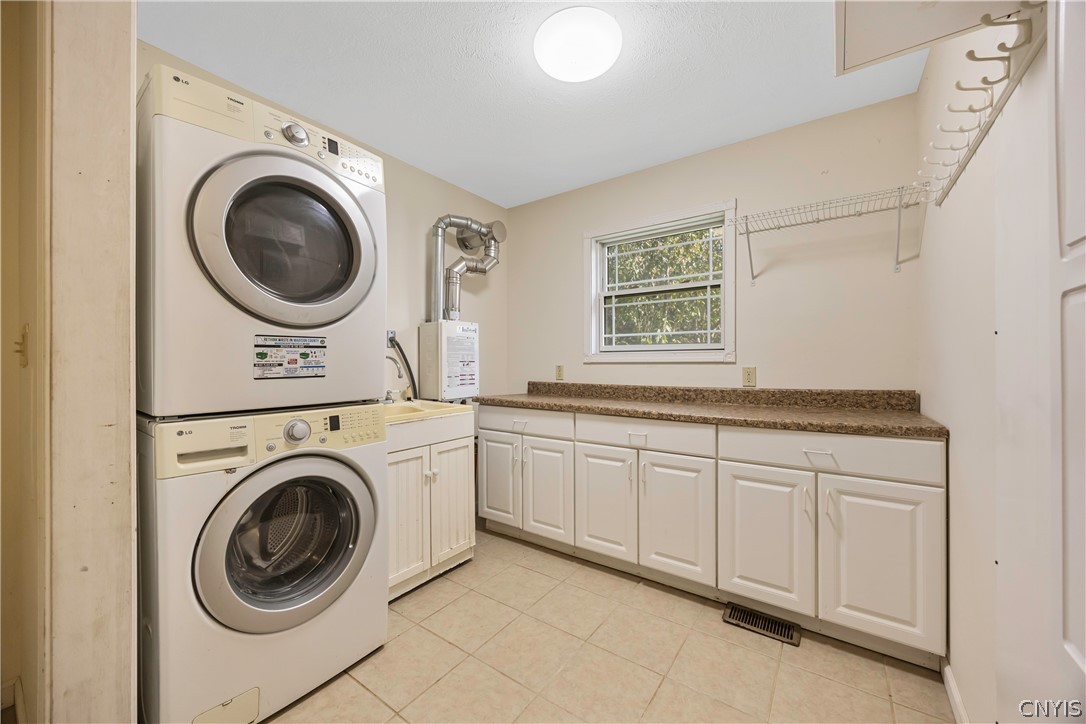 3985 Williams Corners Road Eaton, NY 13408 - Photo 32 of 48 Laundry room with lots of storage and utility sink. On demand gas hot water (tankless) unit. There is also a built- in ironing board in the cabinet to the right