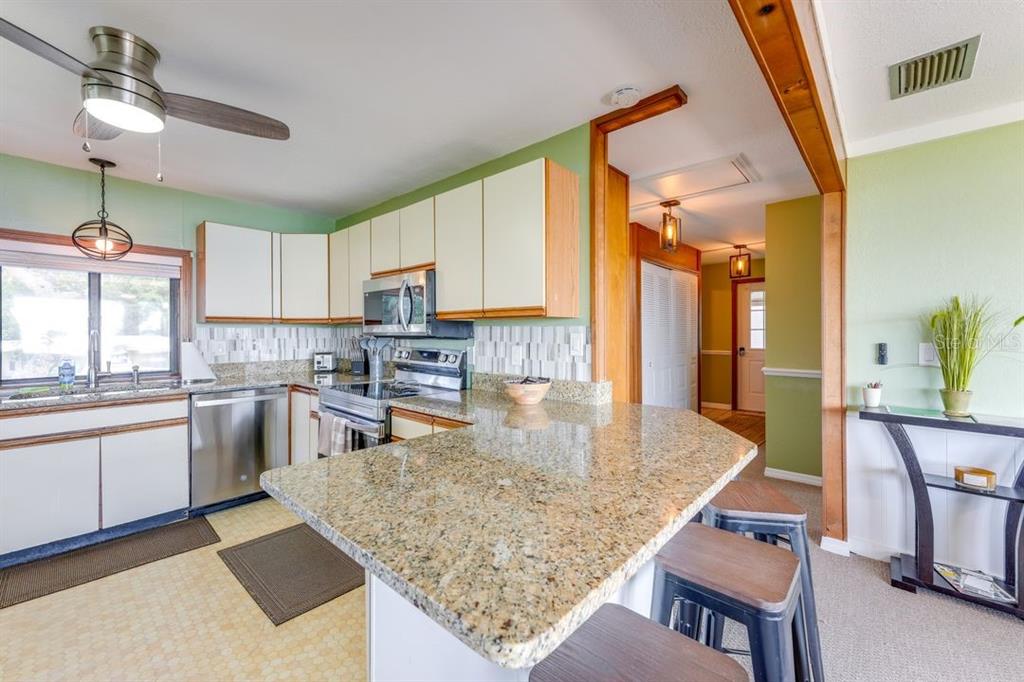900 North Harbor Terrace Road Tavares, FL 32778 - Photo 30 of 58 a kitchen with kitchen island granite countertop wooden cabinets a counter top space and stainless steel appliances