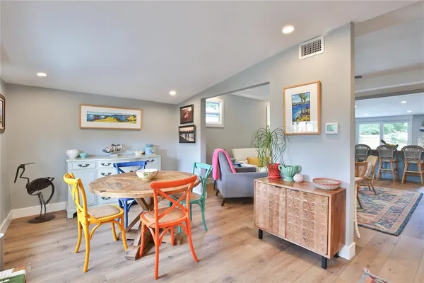 a kitchen with stainless steel appliances granite countertop a stove a refrigerator a dining table and chairs with wooden floor