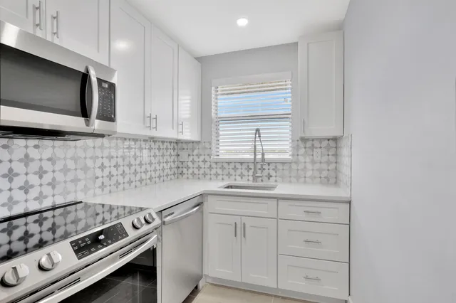 a kitchen with white cabinets stainless steel appliances and a sink