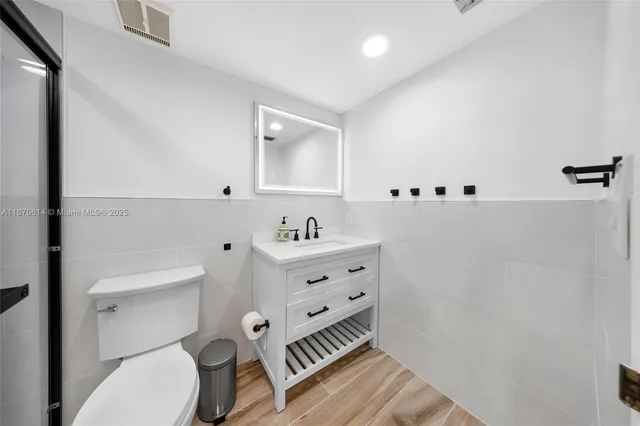 a bathroom with a sink a toilet a mirror and shower