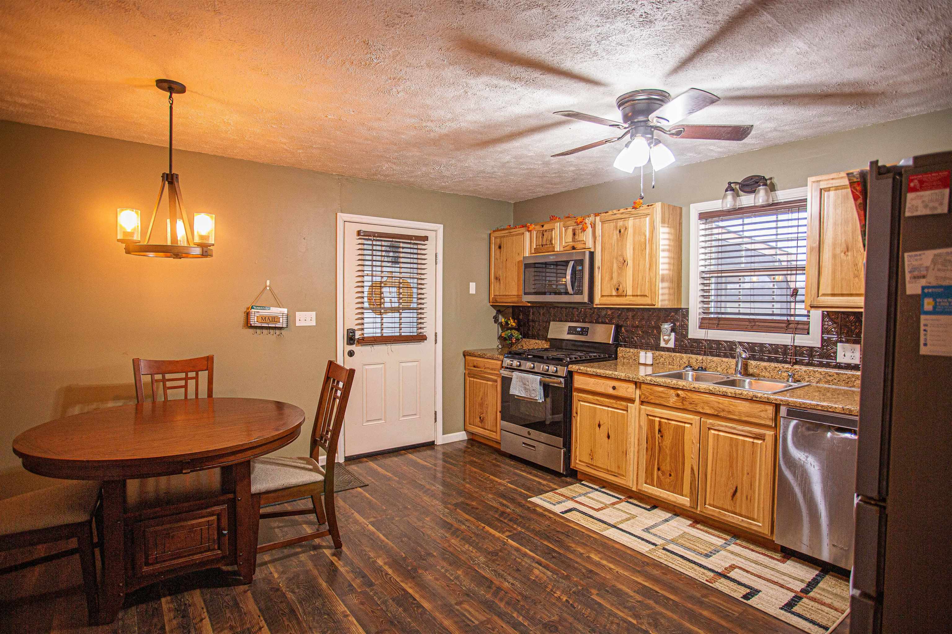 2745 Dry Hill Road West Ripley, TN 38063 - Photo 6 of 23 a kitchen with stainless steel appliances granite countertop a stove a refrigerator a kitchen island a dining table and chairs with wooden floor