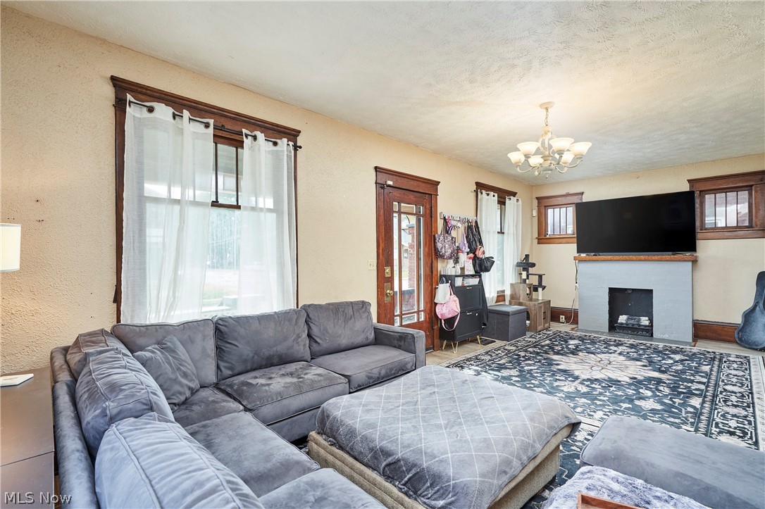 136 Smith Avenue Northwest Canton, OH 44708 - Photo 8 of 19 Spacious living area featuring a decorative fireplace with mantel, dark wood trim around windows and door, and a multi-light chandelier