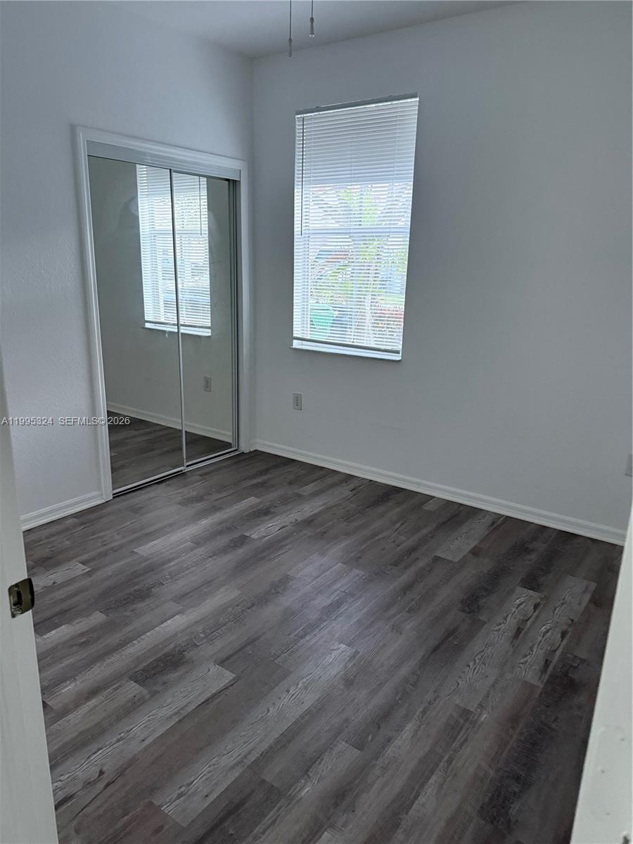 27270 Southwest 138th Court, Unit 1 Homestead, FL 33032 - Photo 5 of 8 an empty room with wooden floor and windows