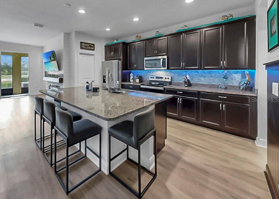 10212 Newel Valley Loop Riverview, FL 33569 - Photo 40 of 72 a kitchen with stainless steel appliances granite countertop a stove top oven a sink dishwasher a dining table and chairs with wooden floor