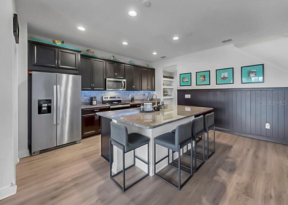 10212 Newel Valley Loop Riverview, FL 33569 - Photo 45 of 72 a kitchen with stainless steel appliances kitchen island granite countertop a refrigerator a stove a sink a dining table and chairs