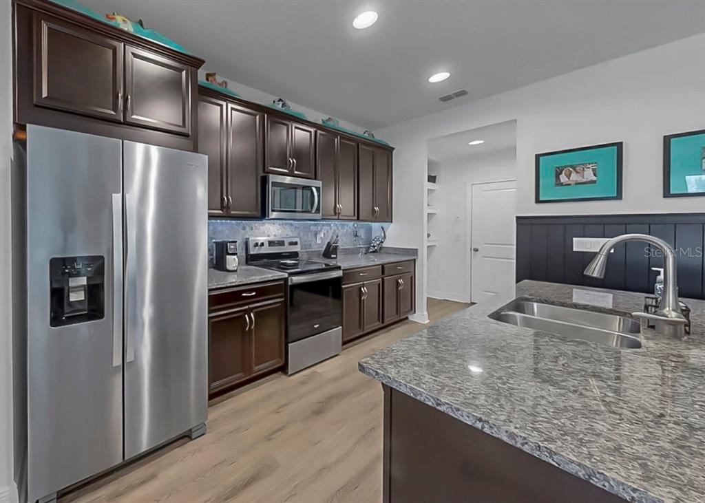 10212 Newel Valley Loop Riverview, FL 33569 - Photo 46 of 72 a kitchen with stainless steel appliances granite countertop a refrigerator a stove and a sink with wooden floor