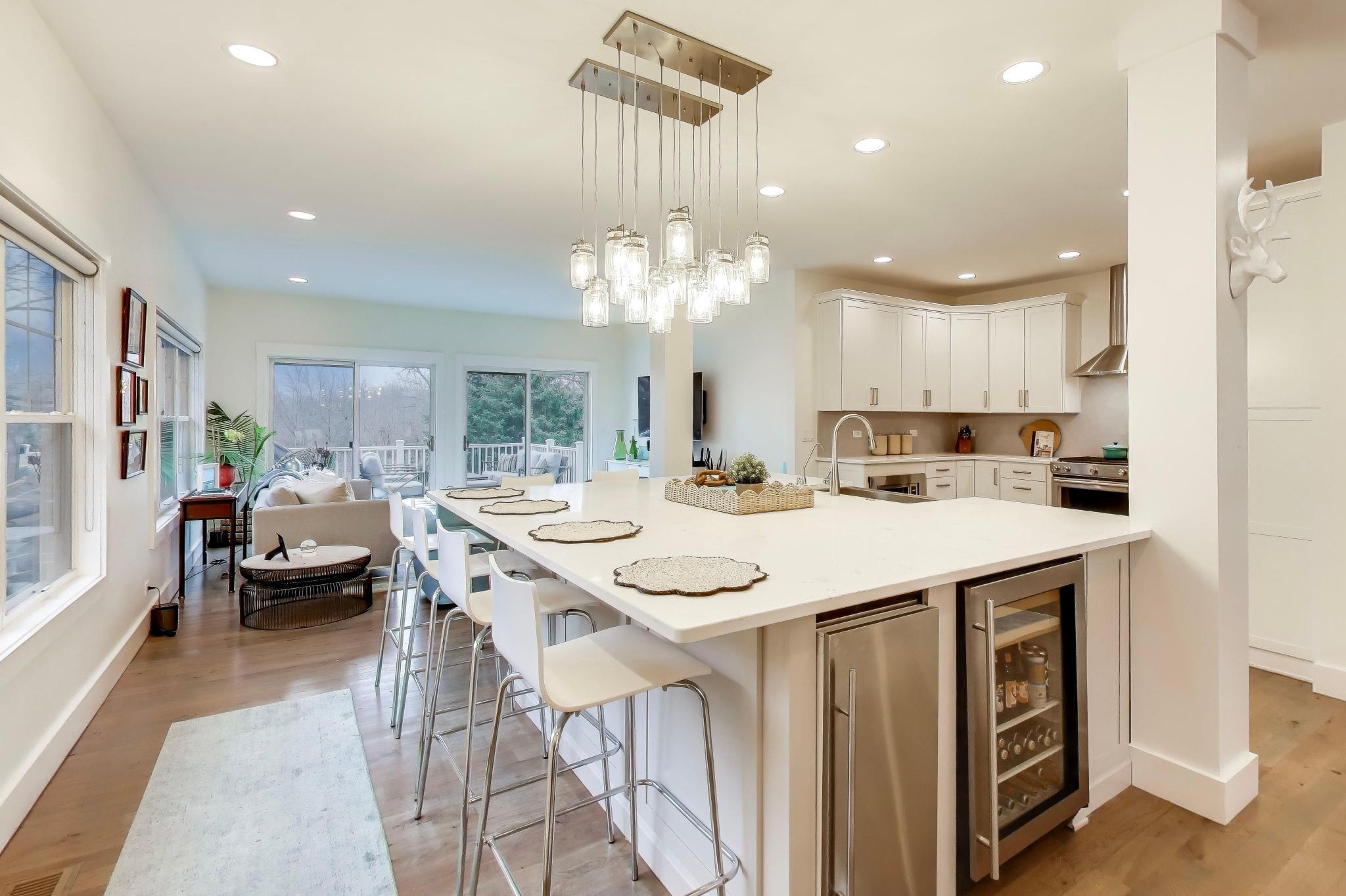 603 Agaming Road Fontana, WI 53125 - Photo 10 of 68 Expansive quartz island with seating anchors this open kitchen, complemented by custom cabinetry, stainless steel appliances, and statement pendant lighting.