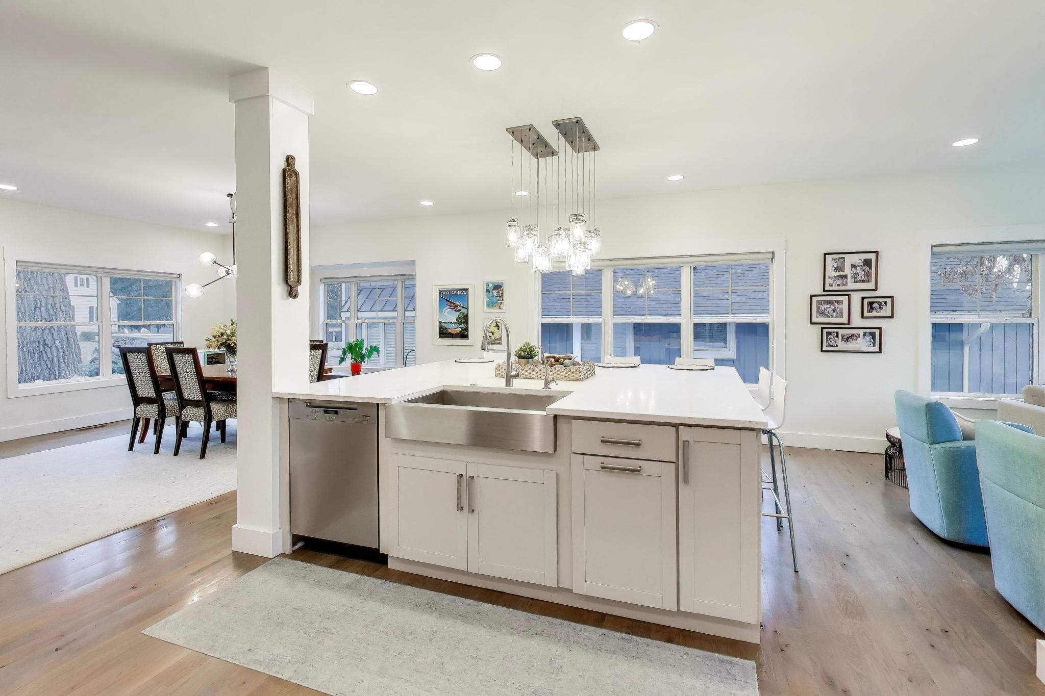 603 Agaming Road Fontana, WI 53125 - Photo 13 of 68 Bright kitchen featuring quartz countertops, a farmhouse stainless steel sink, stainless steel appliances, and custom cabinetry, all flowing seamlessly into the main living areas.