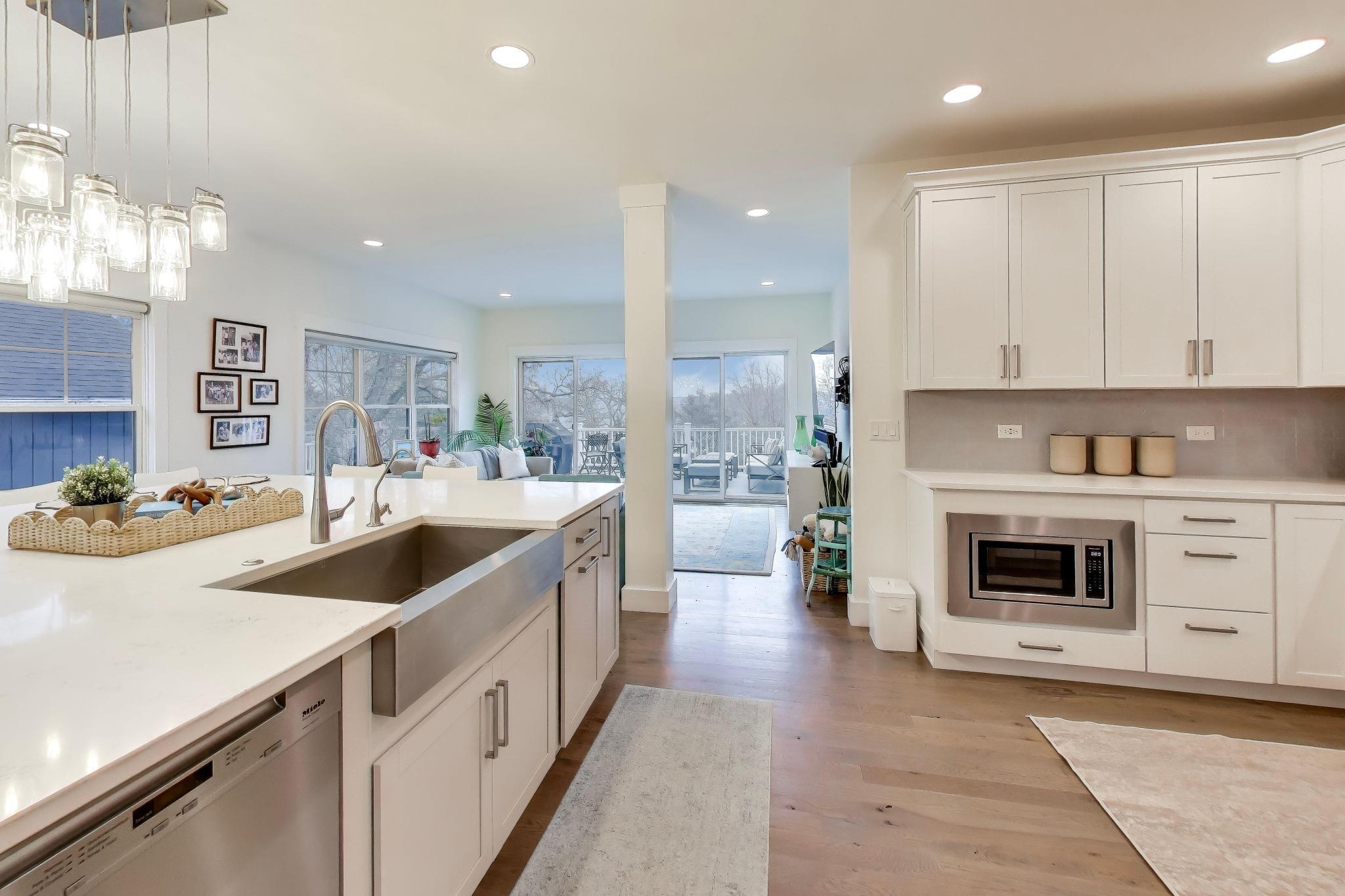 603 Agaming Road Fontana, WI 53125 - Photo 14 of 68 Bright kitchen featuring a large farmhouse sink, quartz countertops, custom cabinetry, and a spacious island that anchors the open-concept layout.